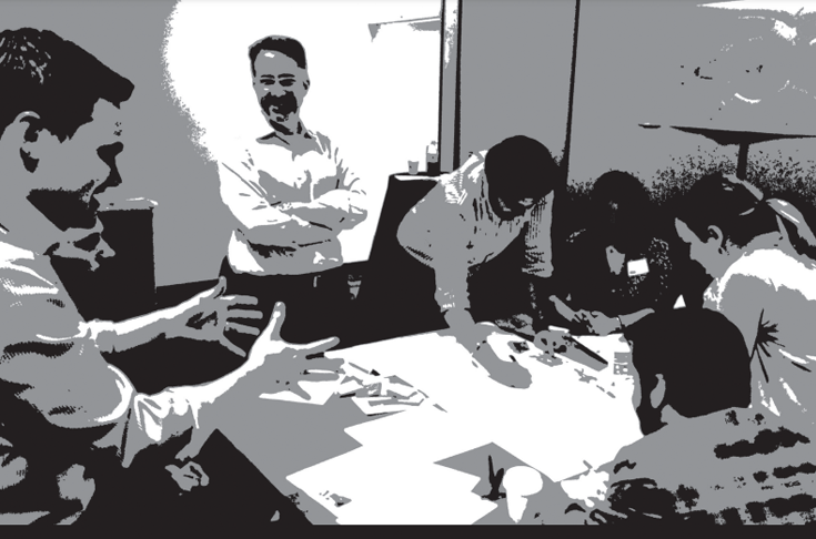 Black and White picture of a group of people around a table talking