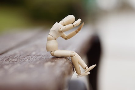 Wooden doll sitting on a bench